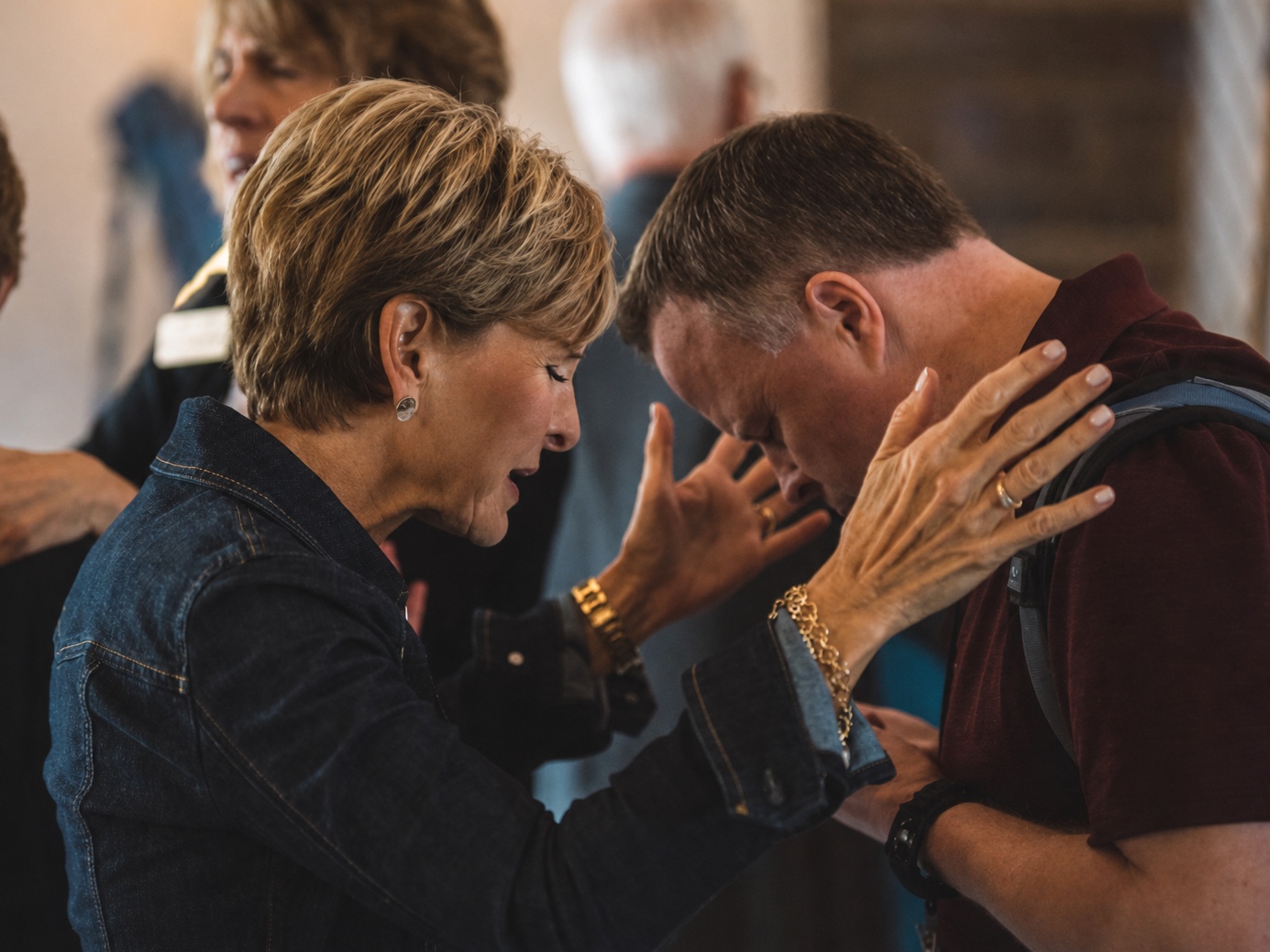 Sheree laying hands on a man in prayer during a ministry gathering